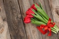 Bouquet of red blooming tulips with green stems and leaves tied with a red silk ribbon Royalty Free Stock Photo