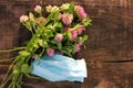 Bouquet of red clover flowers and blue pandemic face mask on wooden background outdoors. Spring or summer still life Royalty Free Stock Photo