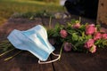 Bouquet of red clover flowers and blue pandemic face mask on wooden background outdoors. Spring or summer still life Royalty Free Stock Photo