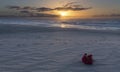 Bouquet of red flowers on beach at sunrise with cloudy sky Royalty Free Stock Photo