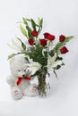 Bouquet of red flowers in vase with bear toy