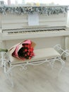 Bouquet of red, pink roses on chair. White piano on background. Royalty Free Stock Photo