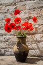 Bouquet of red poppies in clay jug on wooden table Royalty Free Stock Photo