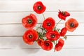 Bouquet of red poppies in glass vase on white wooden table Royalty Free Stock Photo