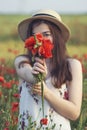 A bouquet of red poppy in the hands of a girl. Walk on the poppy field. Woman walking on a poppy field at sunset with a bouquet of Royalty Free Stock Photo