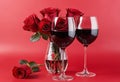 A bouquet of red roses on a red background with an empty wine glass placed in the center Royalty Free Stock Photo