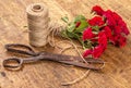 Bouquet of Red Roses, ball of Twine and Old Rusty Scissors on Wooden Table