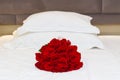 bouquet of red roses on the bed in a hotel room for honeymoon. romantic meeting of guests at the hotel. Royalty Free Stock Photo