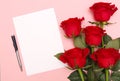 A bouquet of red roses and a blank white sheet of note paper with a pen Royalty Free Stock Photo