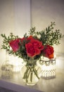 A bouquet of red roses and boxwood in a vase