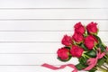 Bouquet of red roses decorated with ribbon on white wooden background. Top view, copy space. Royalty Free Stock Photo