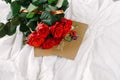 A bouquet of red roses, envelope with congratulation on a background of linen