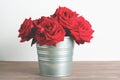 Bouquet of red roses in galvanized bucket on dark wooden table. retro filter