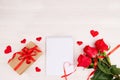 A bouquet of red roses, a gift box with a red ribbon, an empty notebook Royalty Free Stock Photo