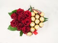 Bouquet of red roses with golden chocolates on a white background.