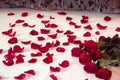 Bouquet from red roses and his scattered petals on a bed