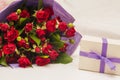 Bouquet of red roses in purple wrapping paper and gift box with purple ribbon on white background. Royalty Free Stock Photo