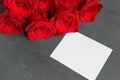 A bouquet of red roses and a sheet of white paper for writing, to write the text on a wooden black background. Royalty Free Stock Photo