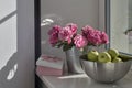 Bouquet of red roses, a steel bowl with green apples and a pink box with the inscription Best wishes on a stone windowsill. Room Royalty Free Stock Photo