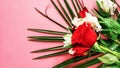 A bouquet of red roses with white flowers and a palm leaf on a pink background Royalty Free Stock Photo