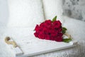 a bouquet of red roses on a wooden tray on a white bed. Royalty Free Stock Photo