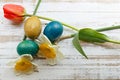 Bouquet of red spring tulip, daffodils and handmade colorful painted easter eggs against rustic wooden background