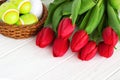 Bouquet red tulip flowers with easter eggs on old wooden table Royalty Free Stock Photo