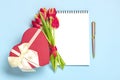 Bouquet of red tulips, gift box heart, notepad on blue background Top view Flat lay Holiday greeting card Happy Royalty Free Stock Photo