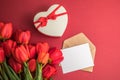 Bouquet of red  tulips and gift heart box isolated on red background . Spring flowers. Greeting card for Birthday, Woman, Mother` Royalty Free Stock Photo