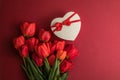 Bouquet of red  tulips and gift heart box isolated on red background . Spring flowers. Greeting card for Birthday, Woman, Mother` Royalty Free Stock Photo