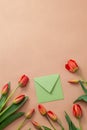 Bouquet of red tulips with kraft green envelope  on a natural beige color background. Mother`s Day, Easter, Valentine`s Day. Royalty Free Stock Photo