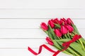 Bouquet of red tulips with red ribbon on white wooden background. Top view Royalty Free Stock Photo