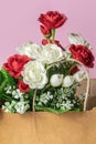 Bouquet of red and white roses in paper bag on pink background, close-up Royalty Free Stock Photo