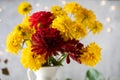 Bouquet of red and yellow flowers in jug against blurred fairy lights Royalty Free Stock Photo