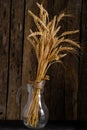 Bouquet ripe wheat ears in glass jug wooden background