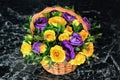 Bouquet of roses on black marble. Yellow and blue flowers in a wicker basket. Composition of flowers on a black background. Purple Royalty Free Stock Photo