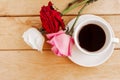 Bouquet of roses and coffee cup on wooden background, top view. Royalty Free Stock Photo