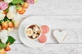 Bouquet of roses, eustomas and hydrangeas on table. Cup of tea or coffee and macaroons. Greeting card for mothers day. Cozy good