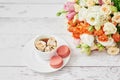 Bouquet of roses, eustomas and hydrangeas on table. Cup of tea or coffee and macaroons. Greeting card for mothers day. Cozy good