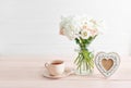 Bouquet of roses, eustomas and hydrangeas on table. Cup of tea and photo frame. Greeting card for mothers day. Cozy good morning. Royalty Free Stock Photo