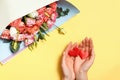 A bouquet of roses and female hands are holding two hearts in the palms on a yellow background. Valentine`s day concept. Royalty Free Stock Photo