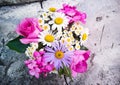 Bouquet of roses, geranium, daisies on a concrete wall with a crack