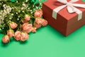 Bouquet of roses and red gift box on green background, copy space, close up, womens day Royalty Free Stock Photo