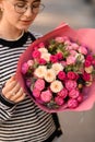 bouquet with roses and thistles in wrapping paper in hands of woman