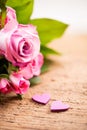 Bouquet of roses with two little hearts on a wooden background Royalty Free Stock Photo