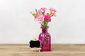 Bouquet of small colored pink carnations in vase, frame on wooden background and grey wall Hello spring, seasonal concept Mock up Royalty Free Stock Photo