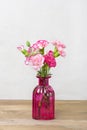 Bouquet of small colored pink carnations in a vase on wooden background and grey wall Hello spring, seasonal concept Mock up Place Royalty Free Stock Photo