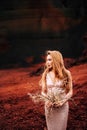 Portrait of a bride model in a golden wedding evening dress, in a yellow-red sandy quarry, in the crater of a volcano in