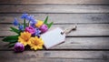 A bouquet of spring flowers with a blank tag, lying on a rustic wooden surface, ready for a personalized message. Royalty Free Stock Photo