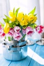 A bouquet of spring tulips of yellow and pink in new saucepans by the window. A gift to a woman. Cozy house. Card